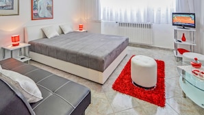 Ein modernes Hotelzimmer mit einem großen Bett, einer Couch, einem Fernseher und einem roten Teppich.