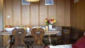 Un coin repas avec une table en bois, des chaises et un vase de fleurs.