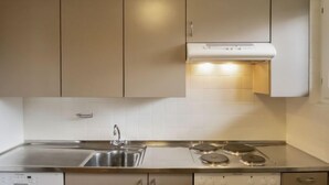 Une cuisine avec des armoires de couleur beige, un évier en acier inoxydable, une cuisinière et un lave-vaisselle.