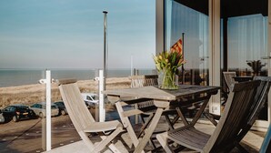 A wooden table with chairs on a balcony overlooking the beach. - De Zeeparel by Interhome (Egmond aan Zee)
