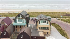 A coastal building complex with a beach view, featuring modern architecture and a paved walkway. - De Zeeparel by Interhome (Egmond aan Zee)