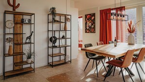 A dining area with a wooden table, black chairs, and a red curtain backdrop. - De Zeeparel by Interhome (Egmond aan Zee)