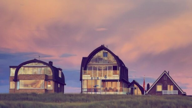 A modern house with a large glass facade, a smaller attached structure, and a traditional house with a chimney. - De Zeeparel by Interhome (Egmond aan Zee)
