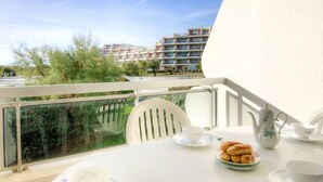 A balcony with a table set for tea, a view of a residential building, and a clear sky. - Apartment Arena by Interhome (La Grande Motte)