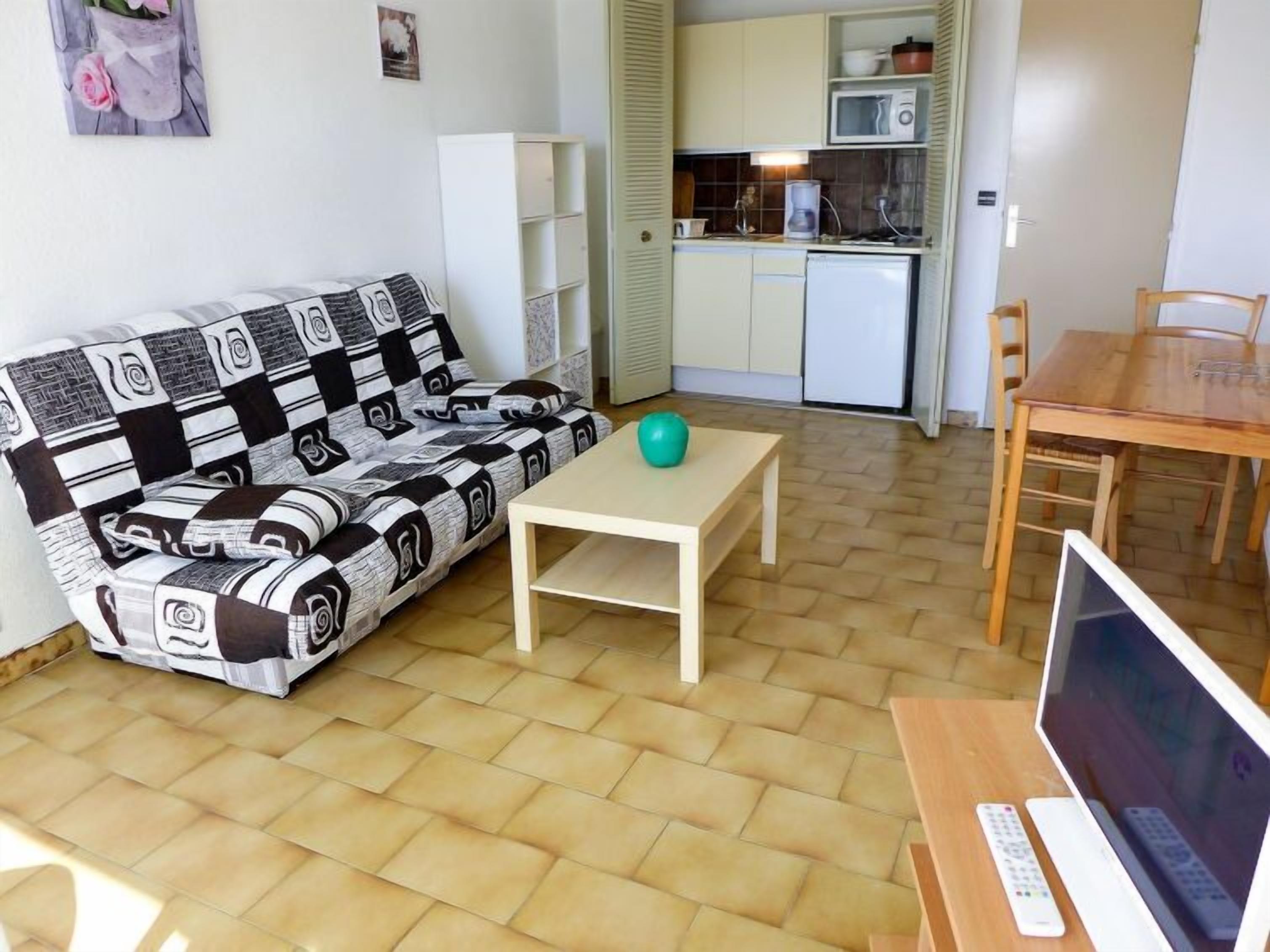 Un espace de vie compact comprenant un canapé, une petite table, une table à manger et un téléviseur.