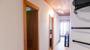 A hallway with a wooden door, a white wall, and a ceiling with wooden beams. - Villars Soleil B15 by Interhome (Villars)