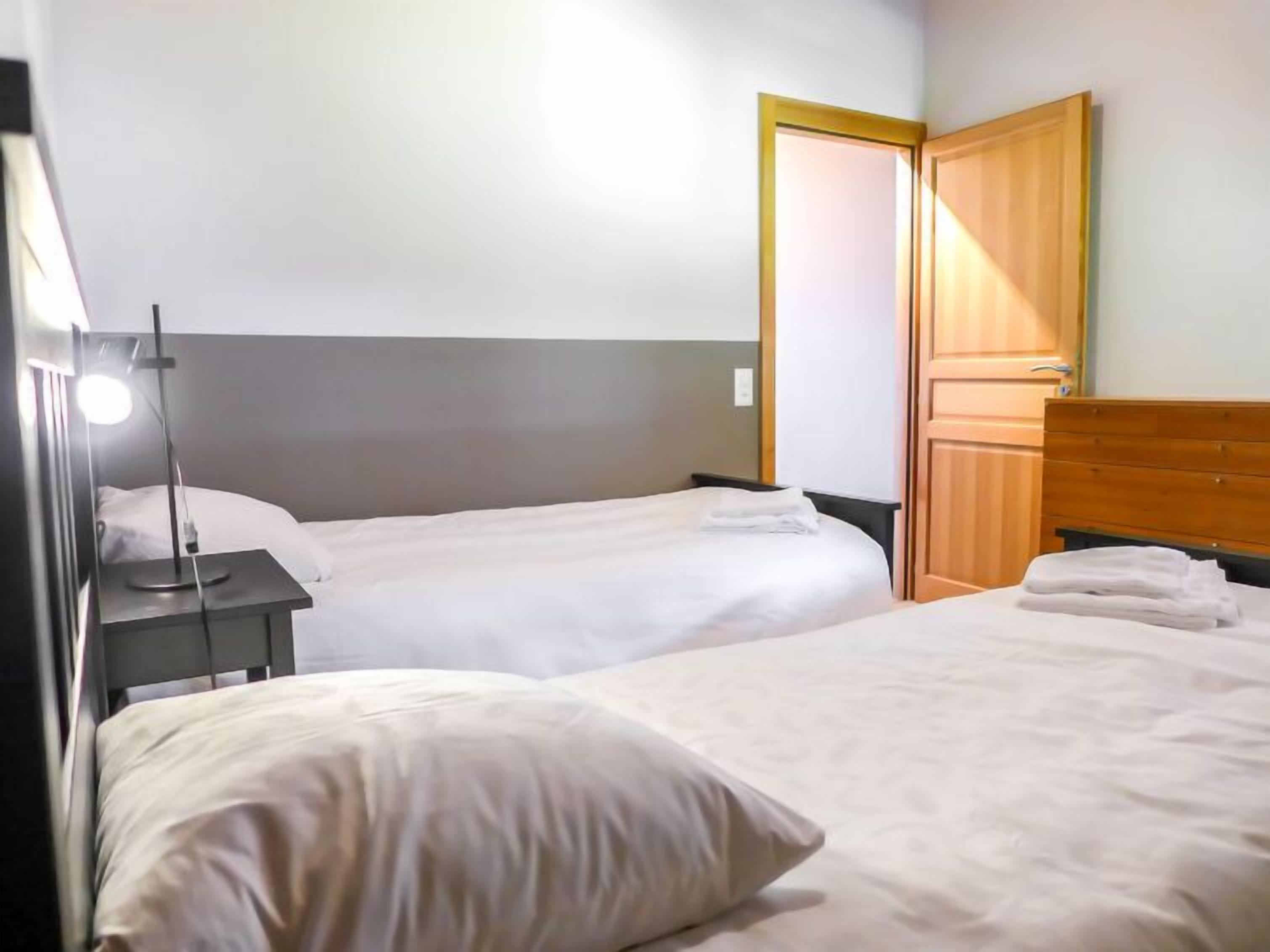 Ein Hotelzimmer mit zwei Betten, einem Nachttisch mit Lampe und einem Holzschrank.