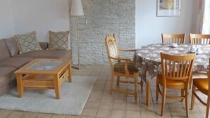 Una sala de estar con un sofá, una mesa de centro y una mesa de comedor con sillas.