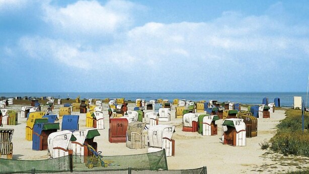 Una playa con numerosas cabañas de playa coloridas dispuestas en filas.