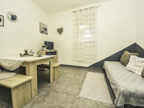 A cozy living room with a wooden desk, a sofa, and a window with sheer curtains. - Snježana by Interhome (Karlobag)