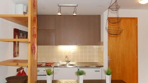 Een moderne keuken met houten kastjes, een roestvrijstalen spoelbak en hangmanden.