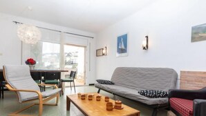 Un salon moderne comprenant un canapé, des fauteuils, une table basse en bois et un coin repas avec une table et des chaises.