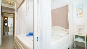 Une chambre à coucher avec un lit à baldaquin, une table de chevet et une lampe fixée au mur.