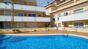 Un immeuble résidentiel à plusieurs étages, avec une piscine en premier plan.