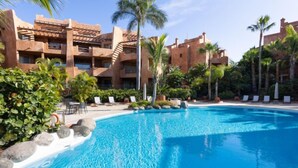 A resort with a large pool, palm trees, and a building with a terracotta facade. - Duplex Bencomo by Interhome (Palm- Mar)