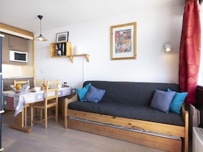 A compact living space with a sofa, dining table, and kitchenette.
