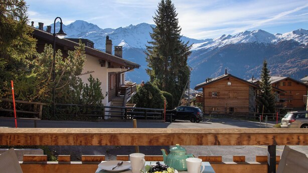 A table set with breakfast items, a mountain view, and a wooden building with a sign reading "Astoria". - Apartment Stem 2 by Interhome (Verbier)