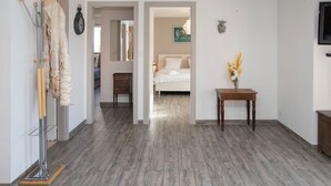 A hotel room with a wooden floor, a bed, a bedside table with a vase of flowers, a coat rack, and a television on the wall. - Apartment Stem 2 by Interhome (Verbier)