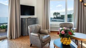 A modern living room with a grey sofa, a round table, and a TV mounted on the wall. - Suite Modern by Interhome (Ascona)