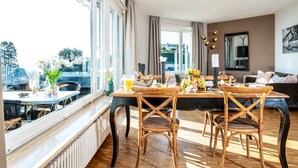 A dining area with a table set for four, large windows, and a view of the outdoors. - Suite Modern by Interhome (Ascona)