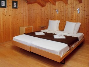 A wooden-paneled room with a bed, a nightstand, and a wall-mounted lamp. - Baudrier A28 by Interhome (Verbier)