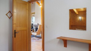 Eine Holztür, die zu einem Raum mit einer hölzernen Bank und einem an der Wand befestigten Regal führt.