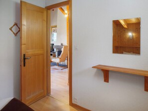 Una porta in legno che dà su una stanza con una panca di legno e uno scaffale a parete.