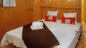 Ein Zimmer mit Holzwänden, einem Bett, Kissen und einem Handtuch.