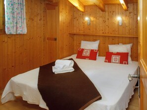 Una stanza con rivestimenti in legno, un letto, dei cuscini e un asciugamano.