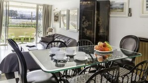 Un espace repas moderne avec une table en verre, des chaises noires et un plateau de fruits.