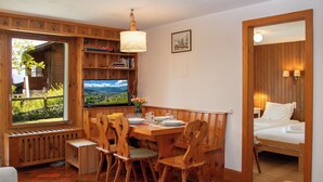 Une pièce chaleureuse avec une table à manger en bois, des chaises, un téléviseur et un lit.