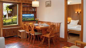 Une pièce chaleureuse avec une table à manger en bois, des chaises, un téléviseur et un lit.