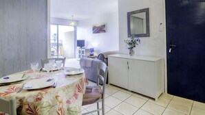 A dining area with a table set for four, a sofa, a cabinet, and a door.