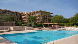 A swimming pool with lounge chairs and a building in the background.