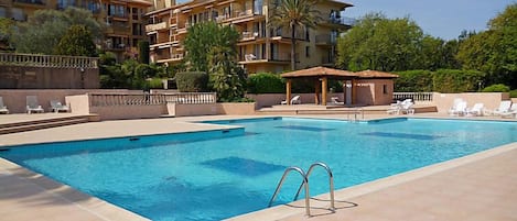 A swimming pool with lounge chairs and a building in the background.