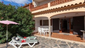 A two-story building with a balcony, stone patio, and outdoor seating area. - Adelfa apt. 1 by Interhome (L'Escala)