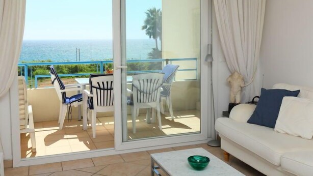 Ein Balkon mit Blick aufs Meer, ein weißes Sofa und zwei Stühle.