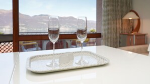 Een dienblad met twee glaasjes water op een tafel, met uitzicht op bergen door een raam.