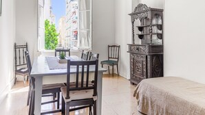 Een kamer met een eettafel, stoelen, een bed en een decor kast.