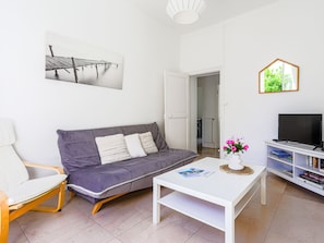 A modern living room with a grey sofa, a white coffee table, a white armchair, a TV on a white stand, and a bookshelf. - Apartment Hérold by Interhome (Nice)