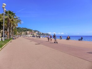 A coastal promenade with palm trees, a clear sky, and people walking and riding scooters. - Apartment Hérold by Interhome (Nice)
