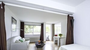 Camera d'albergo moderna con un letto grande, un divano, un tavolo da pranzo e vista sull'esterno.