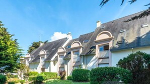A row of townhouses with a curved driveway, surrounded by well-maintained greenery and trees. - Rose des Vents by Interhome (Quiberon)