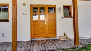 Une porte en bois avec une plaque portant un numéro, une petite fenêtre et un banc en bois devant un bâtiment.