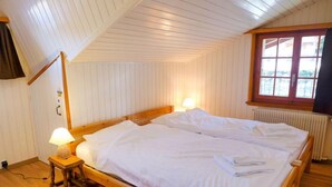Ett rum med en säng i trä, två sänglampor, ett fönster med utsikt och ett element.