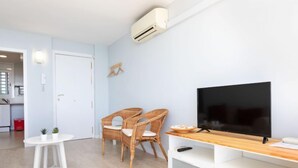 A modern living room with a flat-screen TV, two wicker chairs, a small white table, and a white entertainment unit. - Clipper by Interhome (Sant Vicenç de Montalt)