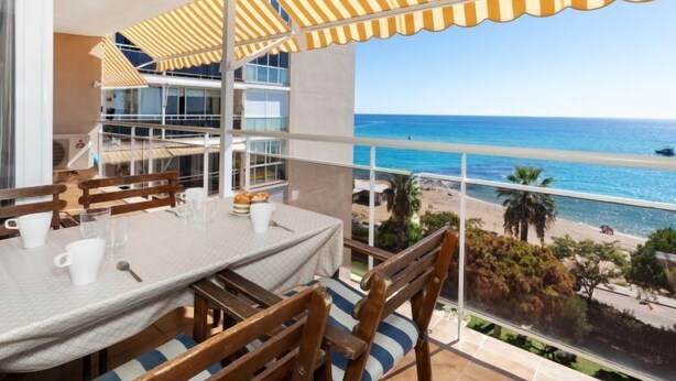 A balcony with a table and chairs, overlooking a beach and ocean. - Clipper by Interhome (Sant Vicenç de Montalt)