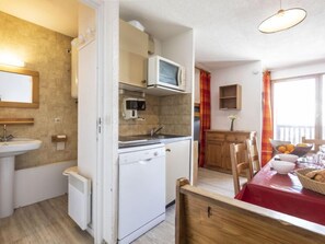 Een koelkast, een oven, een vaatwasser, kookgerei, borden en bestek