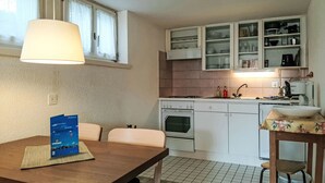 Une cuisine de taille réduite avec des meubles blancs, une cuisinière et un coin repas comprenant une table et des chaises.