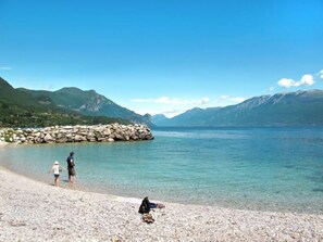 A clear lake with rocky shores and mountains in the background.